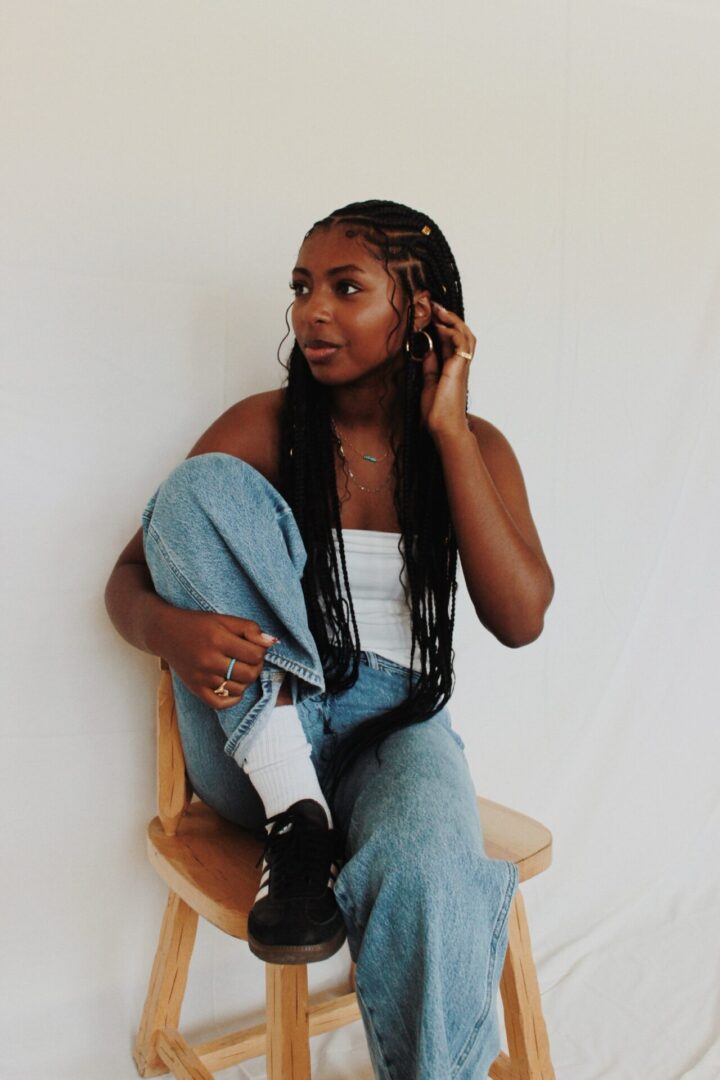Woman sitting on stool in casual attire.