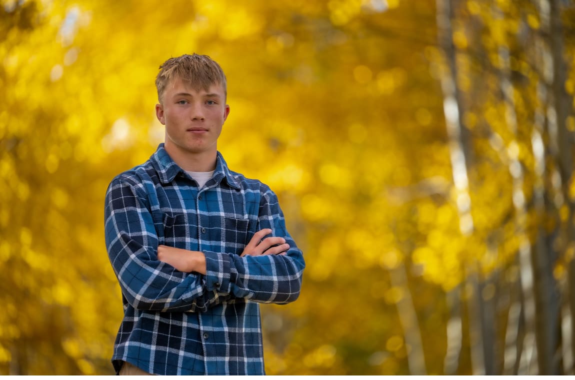 Young man standing in forest with autumn leaves.