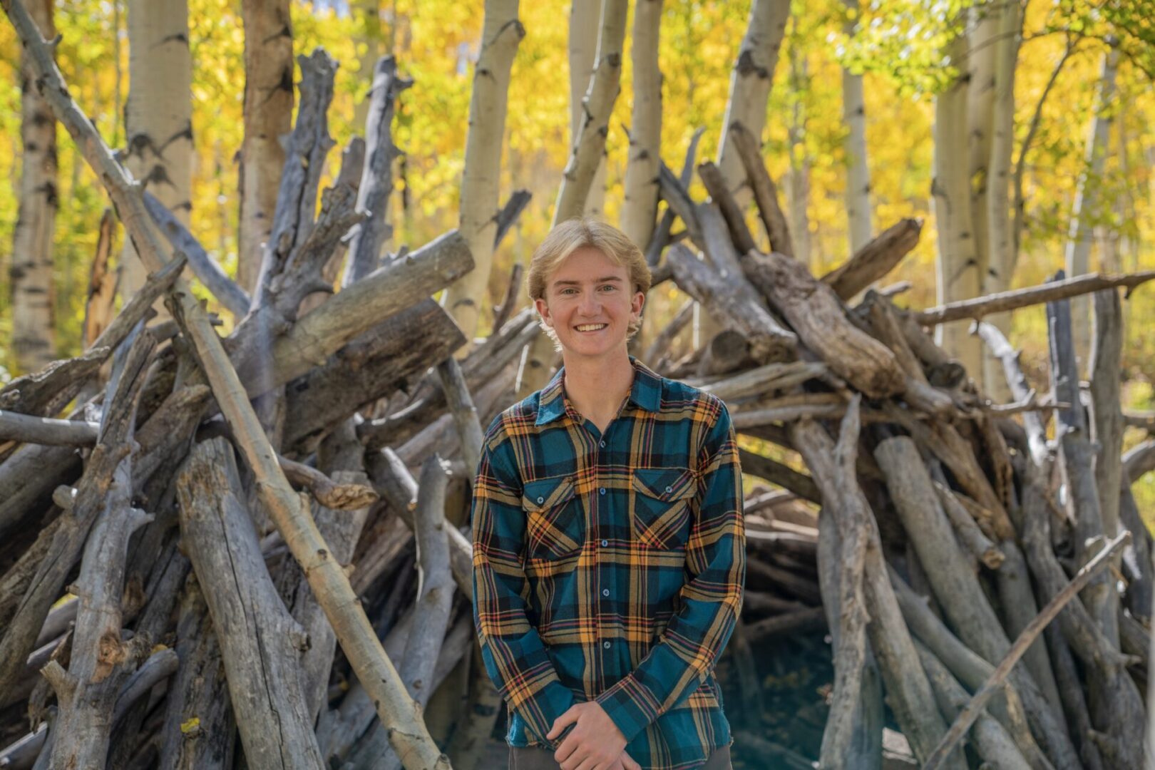 Smiling person in plaid shirt, autumn forest.
