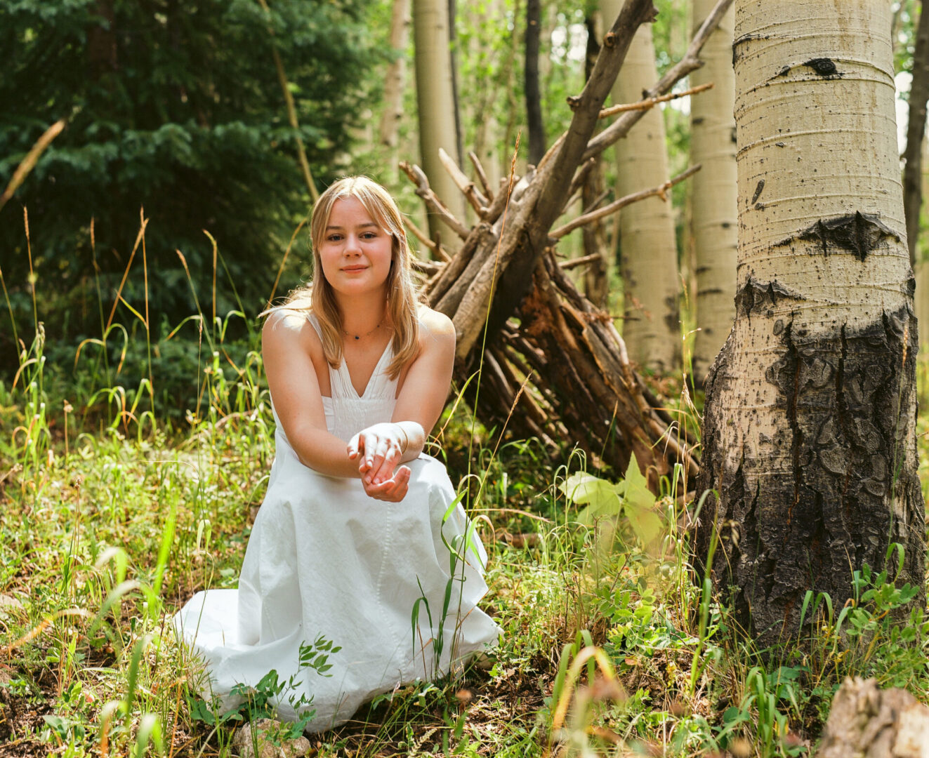 Person in white dress sitting in forest