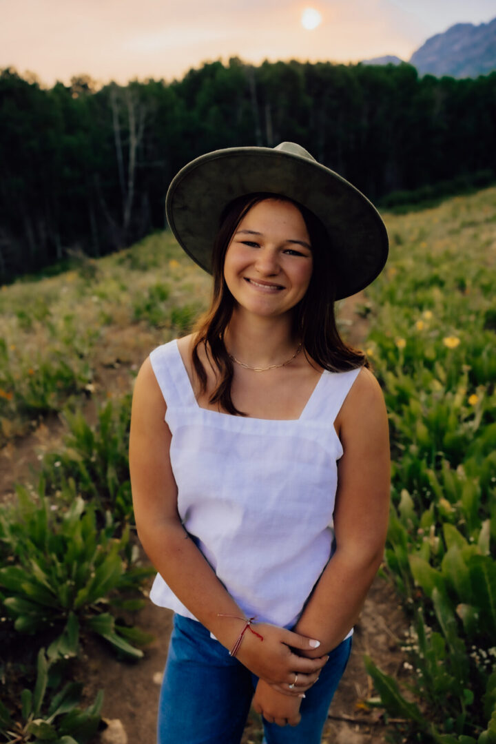 Smiling woman wearing hat in sunlit field