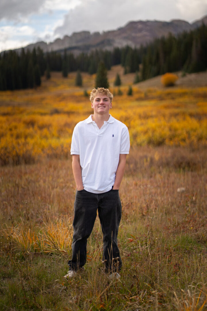 Person smiling in autumn field with mountains