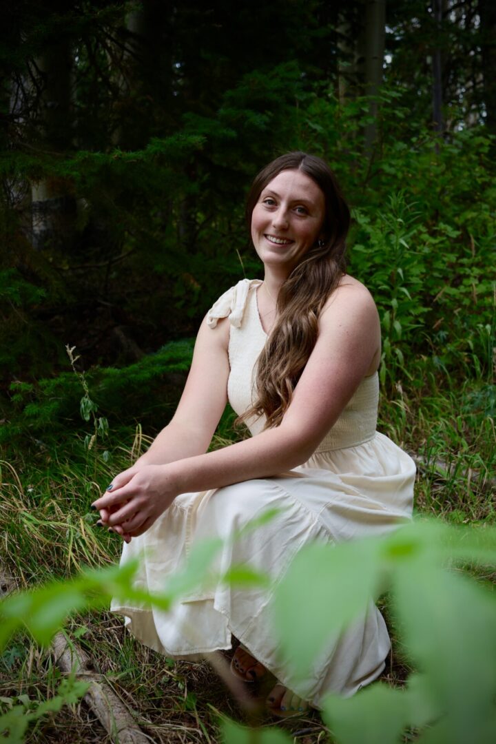 Smiling woman in white dress sitting outdoors