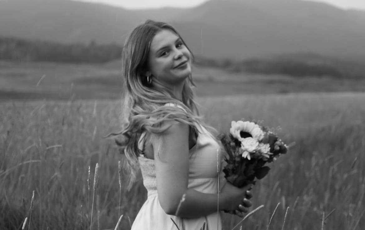 Smiling woman holding bouquet in grassy field