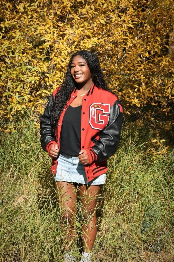 Smiling woman in red letterman jacket outdoors